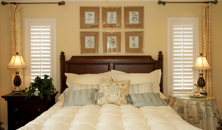 Tall plantation shutters framing bed in a bedroom in Cincinnati 